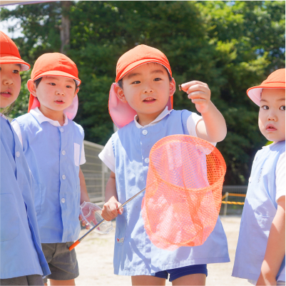 子どもたちが網を持って虫取りをしている写真